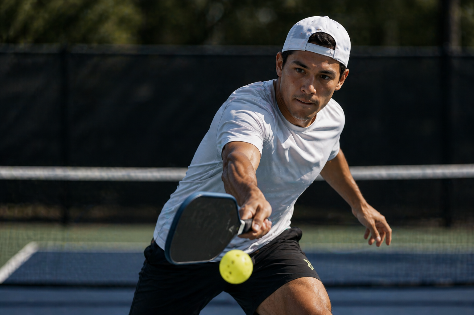 A pickleball player driving a ball from the baseline